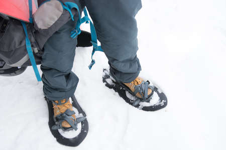 A sporty man putting on his snowshoes to start a snowy mountain excursion. He loves winter sportsの写真素材