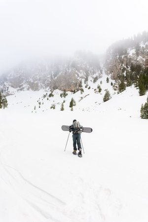 Free rider with snowshoes and snowboard on his back, contemplating the snowy landscape around himの写真素材
