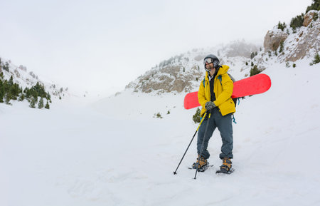 A sporty man putting on his snowshoes to start a snowy mountain excursion. He loves winter sportsの写真素材