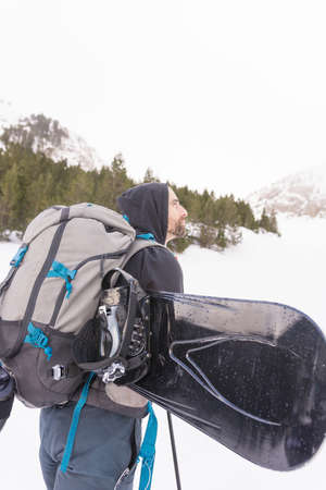 Free rider with snowshoes and snowboard on his back, contemplating the snowy landscape around himの写真素材
