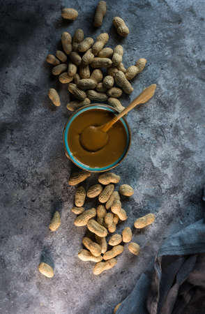 Aerial view photograph of homemade peanut butter in a blue bowl and one hand preparing itの写真素材