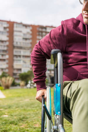 Man in wheelchair taking a walk in the park with a feeling of sadness about his paralysisの写真素材