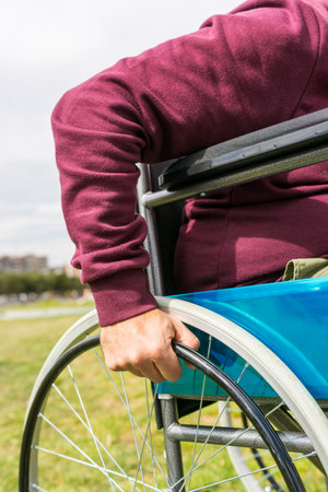 Man in wheelchair taking a walk in the park with a feeling of sadness about his paralysis