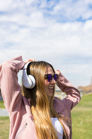 Young and happy girl is dancing while listening to music with her headphones on a spring dayの写真素材