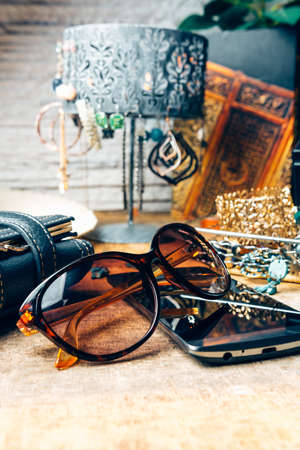Desk full of outfit for women like sunglasses, earrings, mobile phoneの写真素材