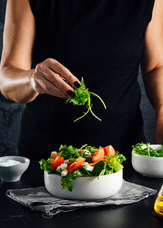 Woman preparing a salad with tomatoes, lettuce, olive oil and salt Concept of healthy dietの写真素材