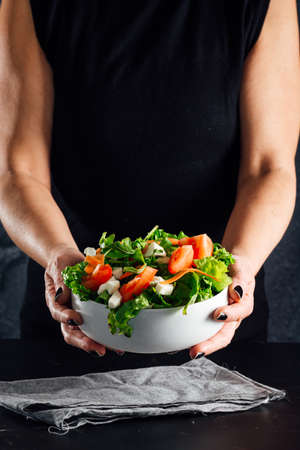 Woman preparing a salad with tomatoes, lettuce, olive oil and salt Concept of healthy dietの写真素材
