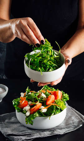 Woman preparing a salad with tomatoes, lettuce, olive oil and salt Concept of healthy dietの写真素材