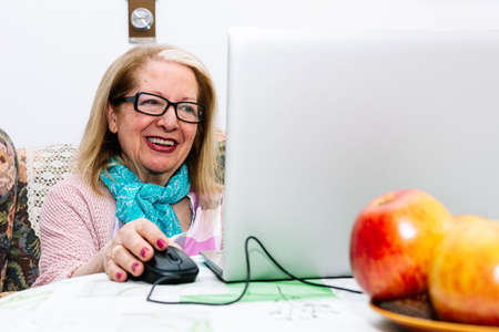 78-year-old grandmother using a laptop at home (concept of technologies for the elderly)の写真素材