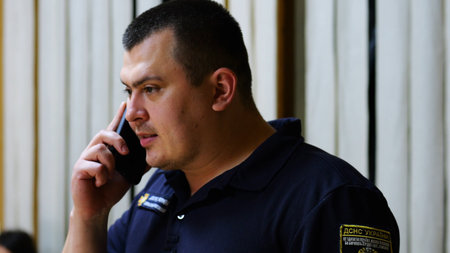 Male firefighter chief have serious telephone conversation with his subordinate by smartphone at fire station. Nervous fireman talking by mobile phone at fire department. Concept of heroic professionの写真素材