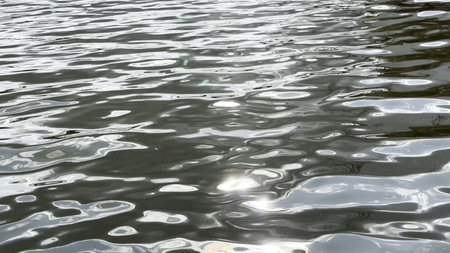 Scenery surface of pond illuminated by sun at summertime. Calm view on sea with small waves at sunny...