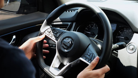 Male arms holds steering wheel while driving a motor car at city. Young man operating the automobile...