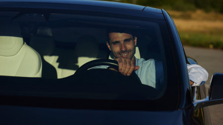 Handsome successful entrepreneur looking through windshield of modern electric car. Portrait of...
