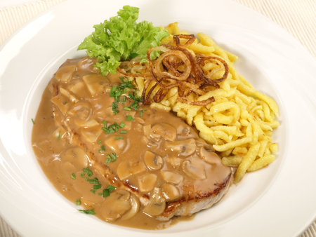 Original Hunter Cutlet with Spaetzle and fried Onions isolated on white backgroundの写真素材