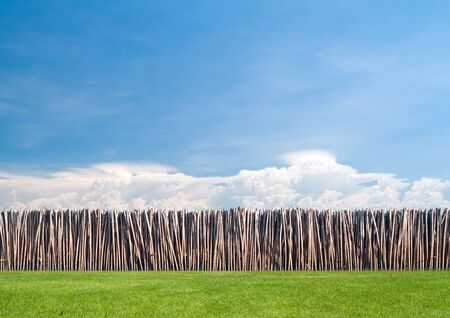 Bamboo wall between beautiful cloud and field of green meadowの写真素材
