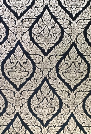 Thai style native art painting on wood door of templeの写真素材