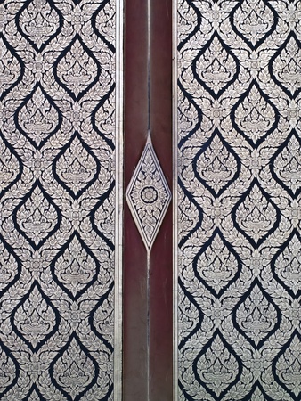 Thai style native art painting on wood door of templeの写真素材