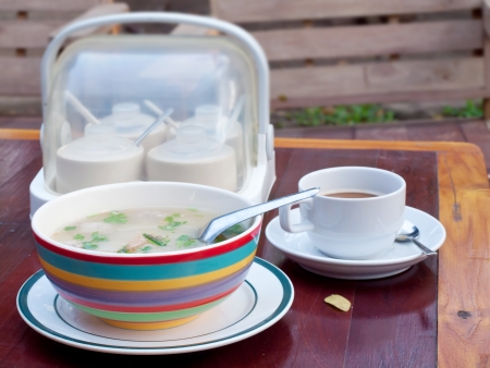 Thai style breakfast soft boiled rice mixed with ground pork, seasoning unit and coffeeの写真素材