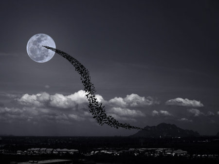 Bats flying again full moon rises over the mountain and village may use for horrible theme or...