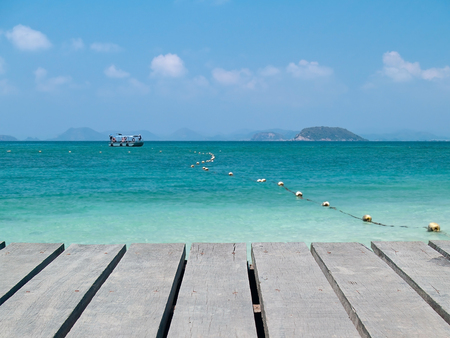 Boardwalk with emerald sea and boatの写真素材