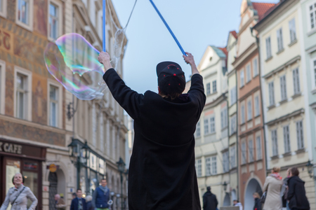 PRAGUE, CZECH REPUBLIC - MARCH 8th, 2014 - Boy makes extra big bubbles in city centerのeditorial素材