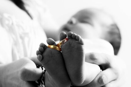 Golden wedding rings on newborn babys feetの写真素材