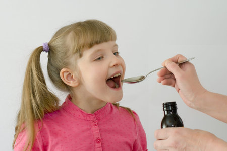 child, kid takes medication from a spoonの写真素材