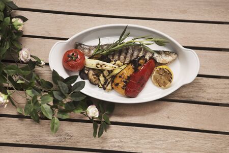 grilled fish with vegetables. Smoked fish on plate on wooden tableの写真素材
