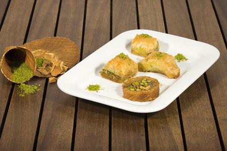 baklava with pistachio. turkish traditional delight on a dark wood background. toning. Turkish sweets on plates. Different oriental sweets on a white plate top view, macroの写真素材