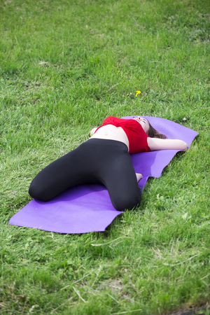 Young girl doing yoga in the park. beautiful girl doing workout on grass in the morning.の写真素材