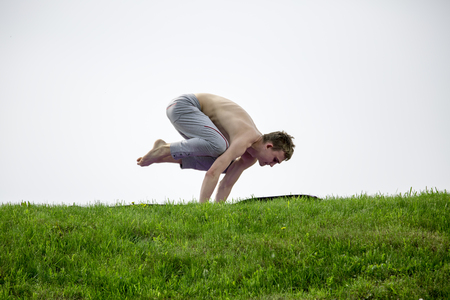Man doing yoga exercises in the park. Fitness yoga man in cobra upward facing dog pose stretching abs stomach muscles. Fit male sports model doing stretching exercise outdoor in summer on grass.の写真素材