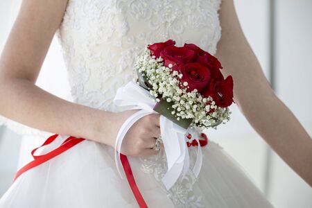 wedding couple hugging, the bride holding a bouquet of flowers in her hand, the groom embracing her. Groom and bride together. Wedding couple.の写真素材