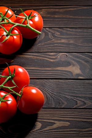 Fresh cherry tomatoes on rustic wooden background. free space on table and red vegetables of tomato on wooden cutting board.の写真素材