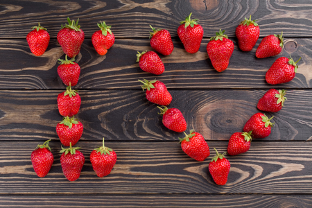 words i love you lettered with fresh organic strawberry isolated on wooden background. Love Confession. Strawberries are laid out in the letters on a background of green grass and board.の写真素材