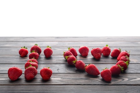 words i love you lettered with fresh organic strawberry isolated on wooden background. Love Confession. Strawberries are laid out in the letters on a background of green grass and board.の写真素材