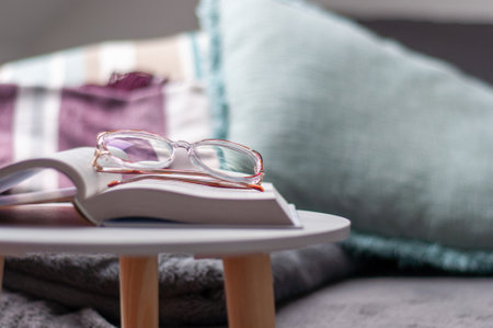 A pair of glasses sits on top of a book on a tableの写真素材