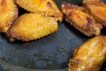 chicken wings are fried in a pan with Barbecued sauce closeup