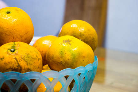 Some oranges in a blue basket over a woodenの写真素材