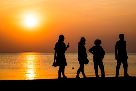 the tourist walk at the beach and sunset silhouette at the beachの写真素材