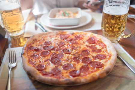 Tasty pizza and glass of beer are on wooden table, close upの写真素材