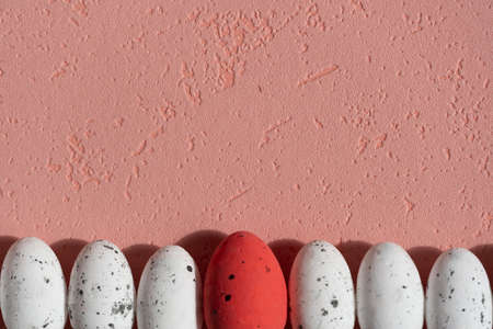 Easter small white eggs and one red egg with black elements on a pink background, text spaceの写真素材