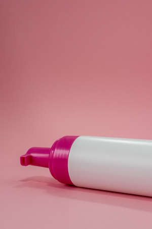 Foam in a bottle, face soap, white bottle with pink tip on pink backgroundの写真素材