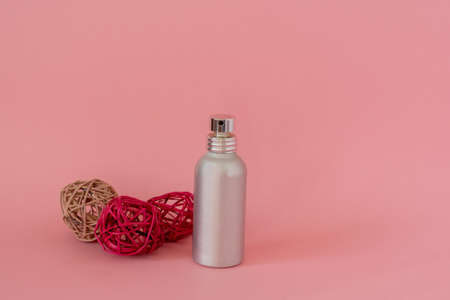 Metallic spray bottle with decorative balls on pink backgroundの写真素材