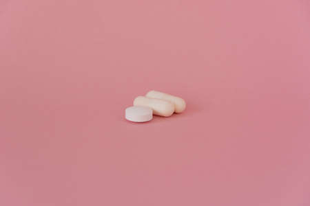 Three white tablets, vitamin tablets, on a pink backgroundの写真素材