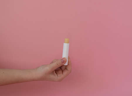 Lip balm in female hand, lips care and beauty, pink backgroundの写真素材