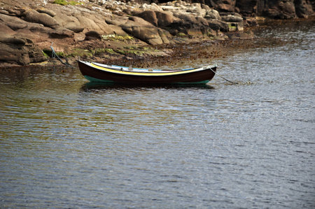 Small boat moored by rocky coastの写真素材