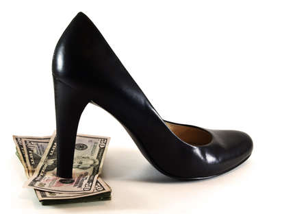 Women's sexy black high heeled shoe stepping on pile of fifty dollar US bills.の写真素材