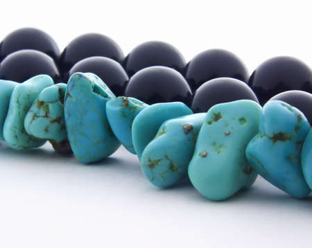Macro of beautiful bright turquoise stone necklace and shiny black pearls isolated on white background. の写真素材