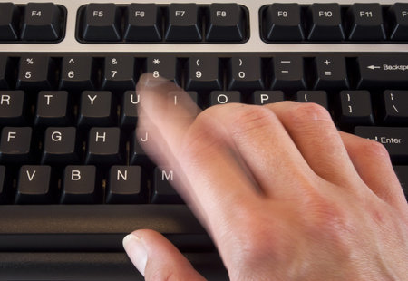 Hand typing on black keyboard with motion blur on finger from typing motion.