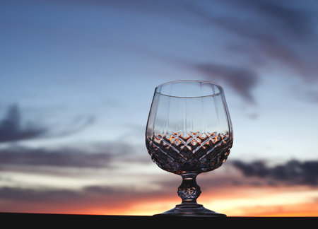 Crystal stem glass against beautiful sunset sky background with copy space の写真素材